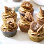 These coffee and walnut cupcakes are rich, nutty, and perfect for any coffee lover. They have a soft and fluffy texture, a delicious coffee flavour, and crunchy walnuts in every bite. Topped with smooth coffee buttercream and a classic butterfly decoration, they are great for afternoon tea, birthdays, or special occasions. In this recipe Mary Berry uses the all-in-one method, making it super easy and foolproof—just mix everything in one bowl and bake! Whether you’re making them for a gathering or just to enjoy with a cup of coffee, these cupcakes are a guaranteed hit. Ingredients Needed For the cupcakes: 2 tsp instant coffee granules 115g (4oz) butter (room temperature) or baking spread (at least 70% fat) 115g (4oz) caster sugar 115g (4oz) self-raising flour 1 tsp baking powder 2 large eggs 45g (1 1/2oz) walnut halves, finely chopped For the icing: 2 tsp instant coffee granules 350g (12oz) icing sugar, plus extra for dusting 175g (6oz) butter (room temperature) 6 walnut halves, halved lengthways How To Make Coffee and Walnut Cupcakes Prepare the oven and coffee: Preheat the oven to 180°C (fan 160°C/350°F/Gas 4). Line a 12-hole shallow bun tin with paper cases. In a small bowl, dissolve the coffee granules in 2 teaspoons of hot water, then set aside to cool. Make the cake batter: In a large bowl, combine the butter, caster sugar, self-raising flour, and baking powder. Add the eggs and the cooled coffee mixture. Using an electric hand whisk or a wooden spoon, beat until the mixture is smooth and creamy. Stir in the chopped walnuts. Bake the cupcakes: Divide the batter evenly between the paper cases. Bake for 15–20 minutes until the cupcakes are well-risen and firm to the touch. Transfer them to a wire rack and let them cool completely. Make the coffee icing: In a small bowl, dissolve the coffee granules in 2 teaspoons of hot water and let it cool. Sift the icing sugar into a large bowl. Add the butter and cooled coffee mixture, then beat until smooth and fluffy. Decorate the cupcakes: Using a sharp knife cut a small circle from the top of each cupcake and cut each piece in half to create “butterfly wings”. Spoon the icing into a piping bag fitted with a star nozzle and pipe a swirl into the centre of each cupcake. Place the reserved cake pieces on top to resemble wings, then add a walnut quarter between them. Lightly dust with icing sugar before serving. Recipe Tips Use soft butter: Let the butter sit at room temperature for 2–3 hours before baking to ensure a smooth mixture. Even baking: Fill the paper cases evenly so that all cupcakes rise at the same rate. Smooth icing: Sift the icing sugar before mixing for a lump-free, creamy texture. No piping bag? Simply spread the icing on top with a butter knife or spoon for an easy alternative. How To Store Leftovers Storing in the fridge: Place the cupcakes in an airtight container and store them in the fridge for up to 3 days. Bring them to room temperature before serving for the best texture. Freezing without icing: Store uniced cupcakes in a freezer-safe container for up to 3 months. Thaw them at room temperature before decorating. Freezing with icing: If freezing with icing, arrange the cupcakes in a single layer inside a container and freeze for up to 2 months. Allow them to thaw in the fridge overnight, then let them sit at room temperature before serving. Try More Recipes: Mary Berry Chocolate Cupcakes Mary Berry Ginger Cupcakes Mary Berry Lemon Cupcakes Mary Berry Carrot Cupcakes