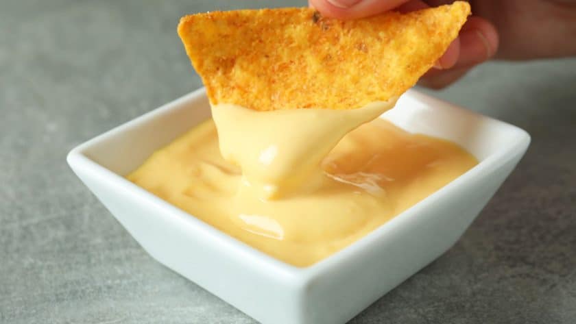 Chip dipping into cheese sauce