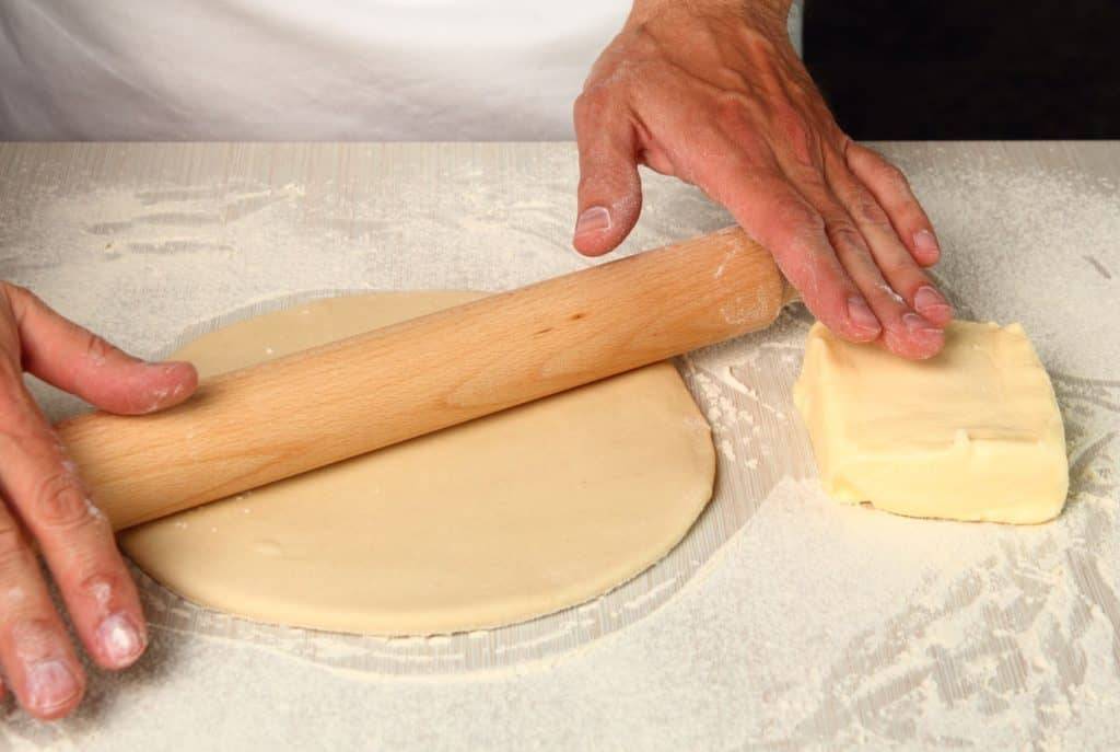 Rolling dough with butter nearby