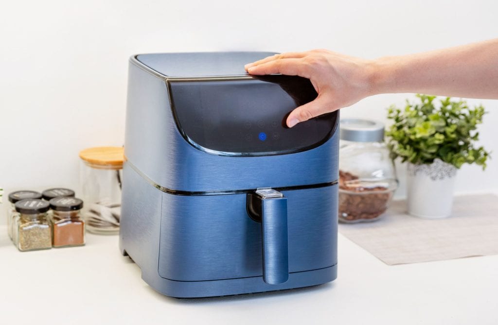 Hand operating a modern air fryer