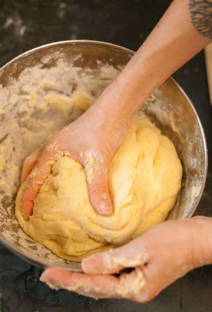 Hands kneading dough in a bowl