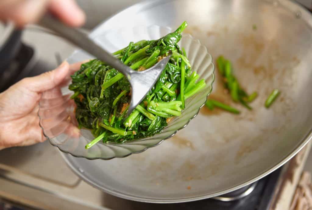 Person serving sautéed green vegetables
