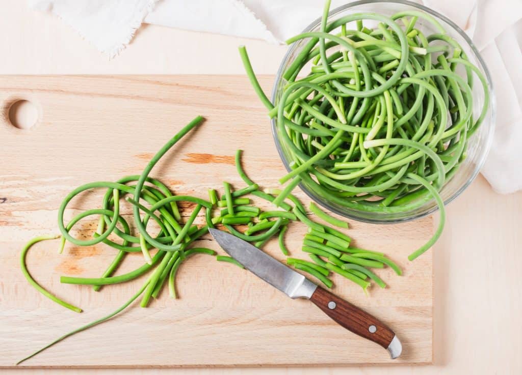 Fresh garlic scapes on wooden board