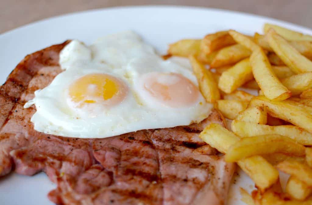 Grilled meat with fried eggs and fries